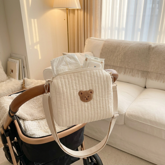 BearHug Quilted Pram Caddy hanging on a pram handlebar in a cosy winter living room with warm lamp light