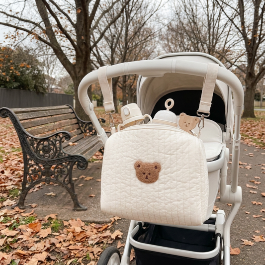 BearHug Quilted Pram Caddy clipped to a white pram in an Australian park in winter with fallen leaves and a park bench